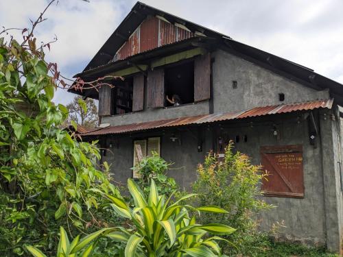 an old house with a broken window and vegetation at Ivy Coffee Farm - Cabin House in Ðưc Trọng