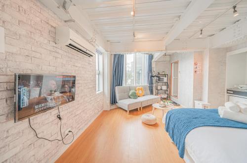 a bedroom with a bed and a tv on a brick wall at Blue Sky Home Osaka Kishinosato Close to Station in Osaka