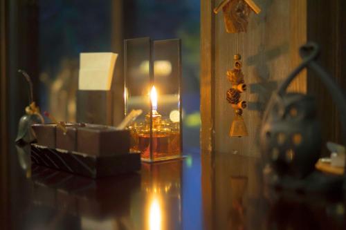 a candle in a glass container on a table at Yamado in Nishiwaga