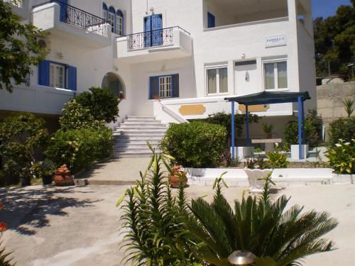 - un grand bâtiment blanc avec des portes et des escaliers bleus dans l'établissement Barbara II, à Agia Marina