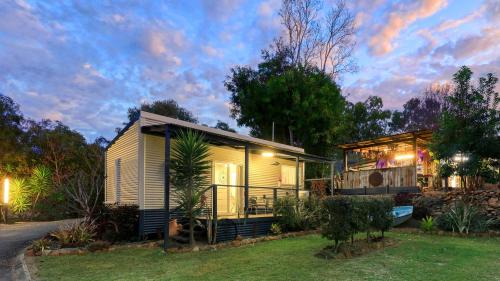 a small house in a yard at dusk at Silver Wattle Cabins in Mount Morgan