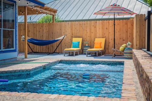 a swimming pool with two chairs and an umbrella at Fun 'n Sun Heated POOL & GameRoom by Fiesta Texas in San Antonio