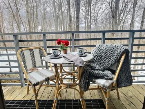 a table and two chairs on a deck at FirBear- AC, Pool, Hot Tub, Sauna, Tennis, Gym in Killington