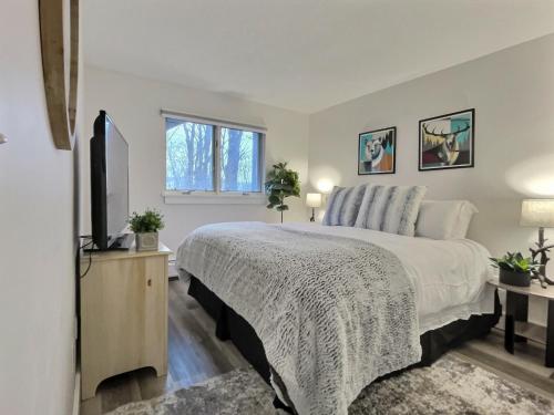 una camera da letto con un letto grande e una televisione di FirBear- AC, Pool, Hot Tub, Sauna, Tennis, Gym a Killington