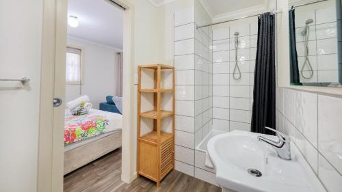 a bathroom with a sink and a bedroom at Silver Wattle Cabins in Mount Morgan