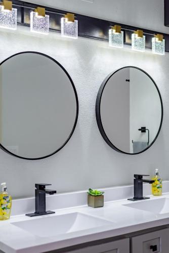 two mirrors above a white sink in a bathroom at Breathtaking Roof Pool Views, Gameroom, Firepit in San Antonio