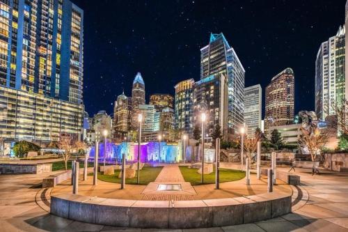 a park with a fountain in front of a city at night at Home Away From Home Charlotte in Charlotte