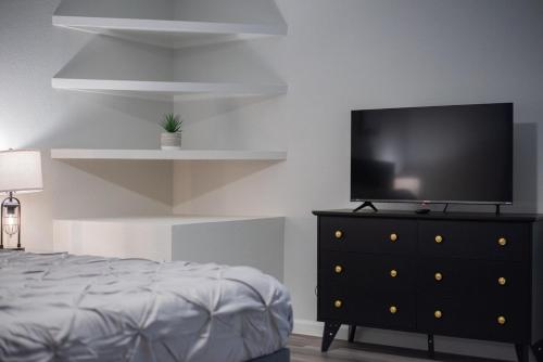 a bedroom with a black dresser with a flat screen tv on it at Luxurious Home With Hot Tub & Tree Deck By 6flags in San Antonio