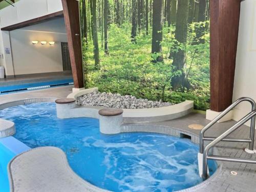 a swimming pool in the middle of a room with a forest at FirBear- AC, Pool, Hot Tub, Sauna, Tennis, Gym in Killington