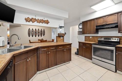 a large kitchen with wooden cabinets and stainless steel appliances at 6 Bed 4 Bath Condo in Waikoloa Village in Waikoloa Village