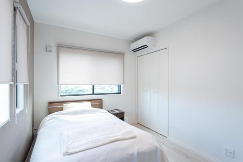 a white bedroom with a bed and a window at Mova Villa Ozu in Ozu