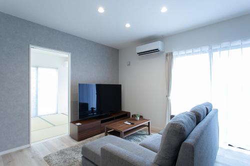 a living room with a couch and a flat screen tv at Mova Villa Ozu in Ozu