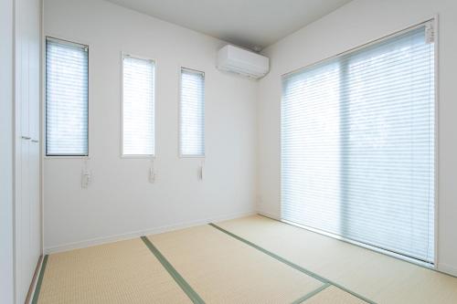 an empty room with white walls and windows at Mova Villa Ozu in Ozu