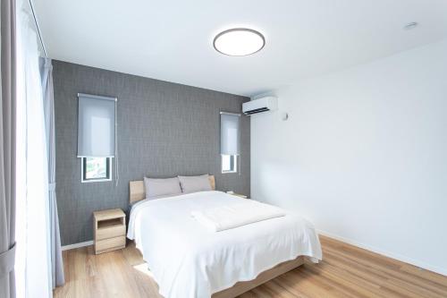 a bedroom with a white bed and a wall with windows at Mova Villa Ozu in Ozu