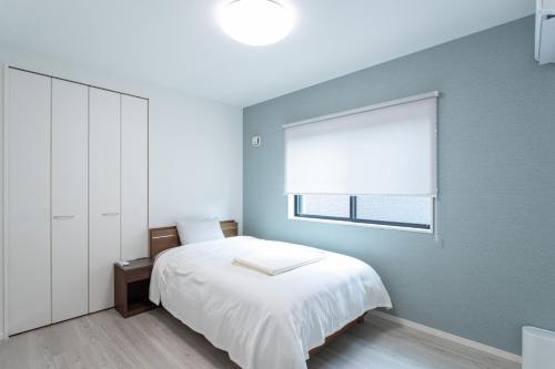 a bedroom with a white bed and a window at Mova Villa Ozu in Ozu