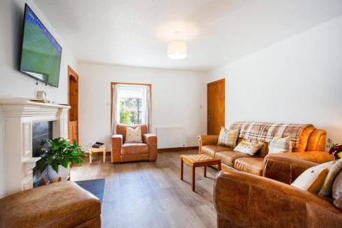 a living room with a couch and a tv at 3BR Cottage with Garden, Free Parking for 6 Guests in Alness