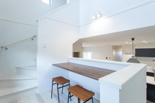 a kitchen with white walls and a counter with two stools at Mova Villa Haramizu in Kikuchi