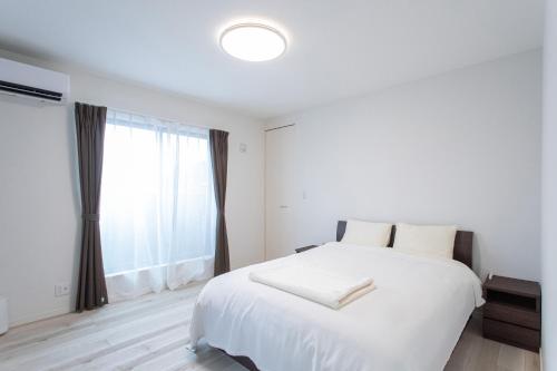 a white bedroom with a white bed and a window at Mova Villa Haramizu in Kikuchi