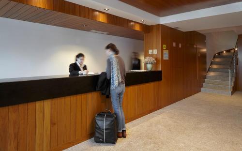 a woman standing at a counter in a lobby at Abrigo da Montanha Hotel Rural in Sabugueiro