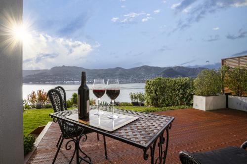 a table with two glasses of wine on a patio at Sanctuary At The Bay - Diamond Harbour Retreat in  Lyttelton