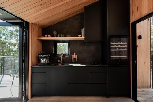 a kitchen with a black counter and a window at Hunter Huon Valley Cabin Three in Glen Huon