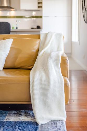 a couch with a blanket on it in a living room at StayAU Magnificent Lakefront Villa Stunning Views in Point Cook