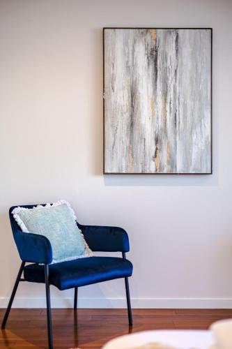 a blue chair in a room with a painting at StayAU Magnificent Lakefront Villa Stunning Views in Point Cook