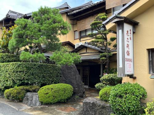 a building with a tree and bushes in front of it at Charoku Bekkan in Miyazu