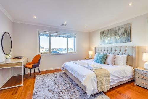 a bedroom with a bed and a desk and a chair at StayAU Magnificent Lakefront Villa Stunning Views in Point Cook