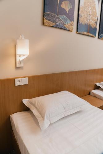 a bedroom with a white bed with two paintings on the wall at Grand Castle Hotel in Urganch