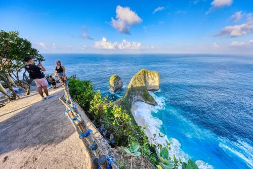 a group of people standing on a cliff overlooking the ocean at Kelingking Beach Villas in Nusa Penida