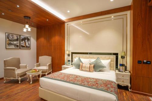 a bedroom with a large bed and a chair at Regenta Place Chandigarh Mohali in Mohali