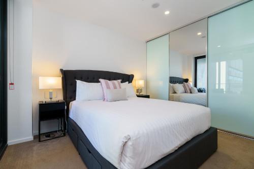 a bedroom with a large bed with white sheets and pink pillows at Contemporary 2BR Retreat in the Heart of Civic - Hosted by Canstay in Canberra