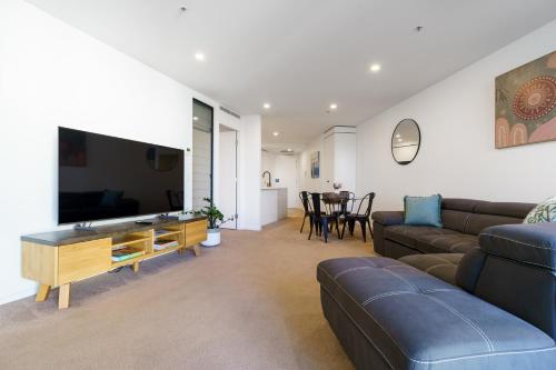 a living room with a couch and a flat screen tv at Contemporary 2BR Retreat in the Heart of Civic - Hosted by Canstay in Canberra