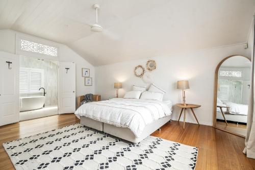a white bedroom with a bed and a bath tub at Frangipani Cottage - Belle Escapes Byron Bay | Winter Escape Deal | Stay Longer & Save | 1 June – 31 August in Byron Bay
