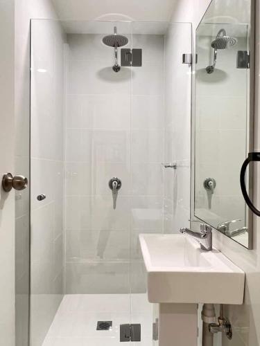 a white bathroom with a sink and a shower at Charming Central Unit in Authentic Building in Sydney