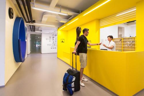 two men standing in a yellow room with luggage at Youth Hostel Proteus Postojna in Postojna