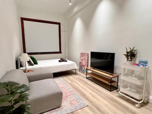a living room with a bed and a flat screen tv at Charming Central Unit in Authentic Building in Sydney