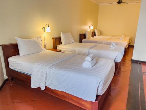 a hotel room with three beds with white sheets at Natural Relax Villa in Siem Reap