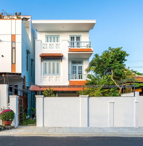 a white house with a white fence at Villa Nautica By The Beach - Vesta Collections in Hoi An