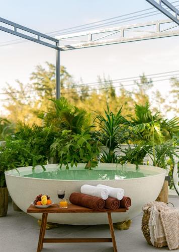 a bath tub sitting in a room with plants at Villa Nautica By The Beach - Vesta Collections in Hoi An