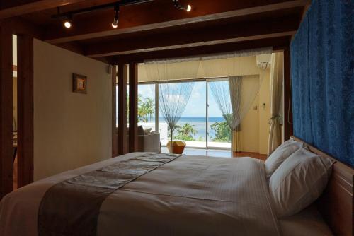 a bedroom with a bed with a view of the ocean at オーシャンヴィラ 海テラス Ishigaki in Ishigaki Island