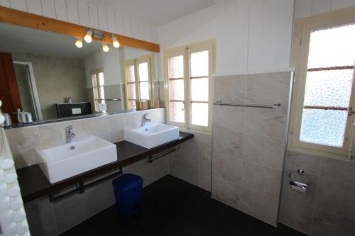 uma casa de banho com 2 lavatórios, um chuveiro e um espelho. em Chalet Les Arolles em Château-d'Oex