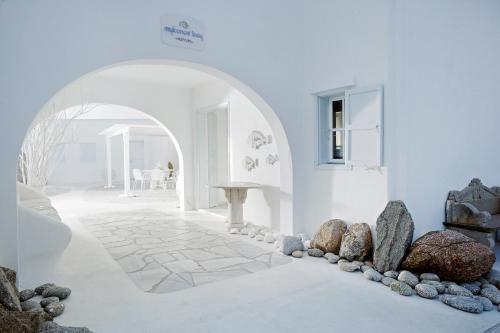 a white room with a stone floor and an archway at Mykonos Bay Resort & Villas in Mýkonos City