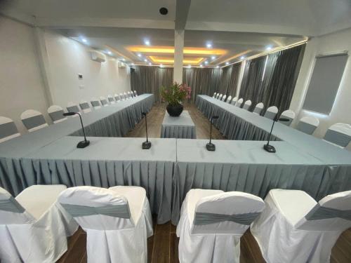 a conference room with white tables and chairs with microphones at Ganesha Kampot Resort in Kampot