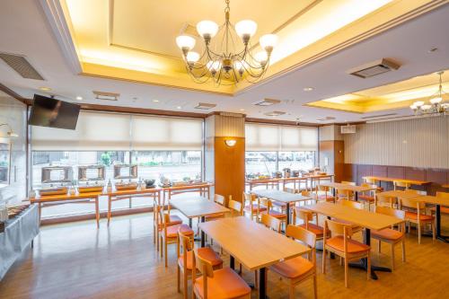 a restaurant with wooden tables and chairs and a chandelier at Kofu Washington Hotel Plaza in Kofu