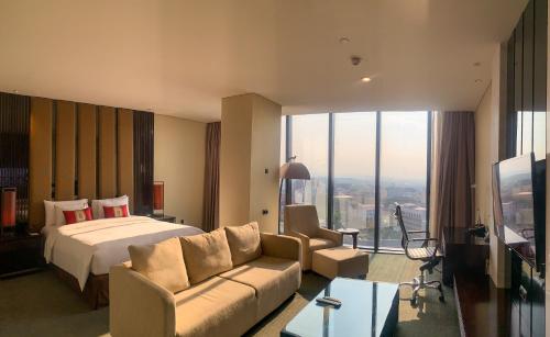 a hotel room with a bed and a couch at PO Hotel Semarang in Semarang