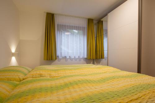 a bedroom with a bed and a window with yellow curtains at Haus Amici in Saas-Almagell