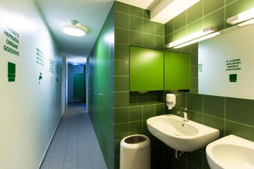 a green tiled bathroom with a sink and a toilet at Youth Hostel Proteus Postojna in Postojna