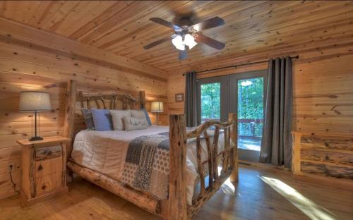 Dormitorio en cabaña de madera con cama y ventilador de techo en Chalet Blue Ridge, en Blue Ridge